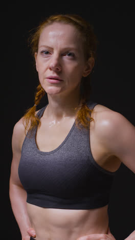 Vertical-Video-Studio-Portrait-Of-Mature-Woman-Wearing-Gym-Fitness-Clothing-Sweating-Recovering-After-Exercise